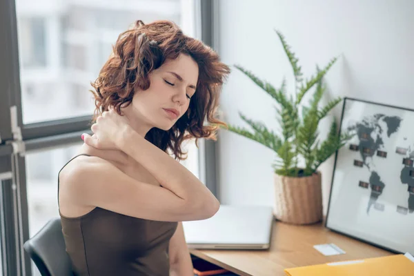 Mulher tocuhing seu pescoço dolorido enquanto descansa depois de um dia de trabalho duro — Fotografia de Stock