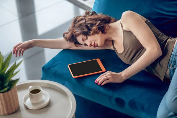 Pretty woman sleeping on the sofa with a tablet next to her