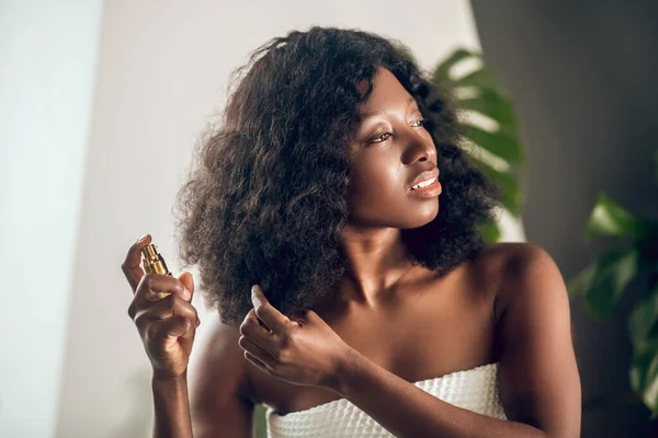 Apelando afro-americano mulher pulverizando soro em seu cabelo — Fotografia de Stock