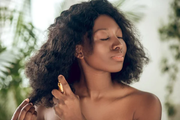 Tilltalande afrikansk amerikansk kvinna sprutar serum på håret — Stockfoto