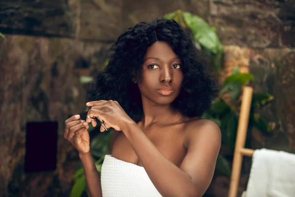Gyönyörű afro-amerikai nő vágja a haját, és úgy néz ki, figyelmes — Stock Fotó