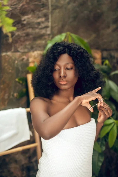 Beautiful african american woman cutting her hair ends