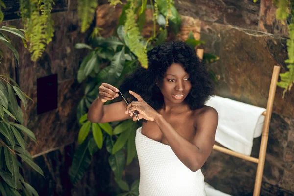 Beautiful african american woman cutting her hair ends — Stock Photo, Image