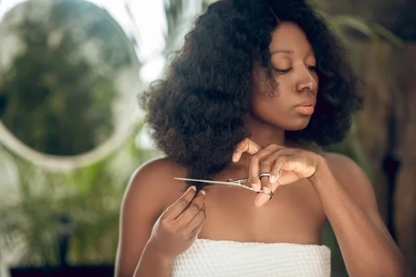 Beautiful african american woman cutting her hair ends — Stock Photo, Image