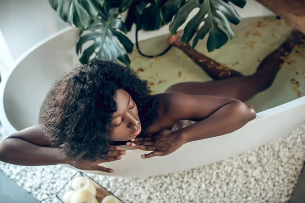 Vékony, sötét bőrű nő, aki a fürdőben pihen. — Stock Fotó