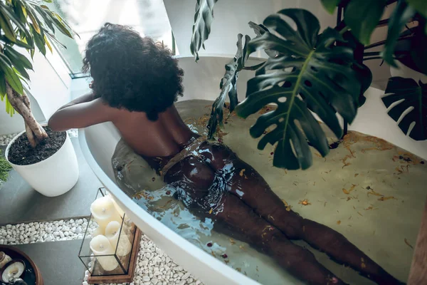 Schlanke dunkelhäutige Frau entspannt sich in einem Bad — Stockfoto