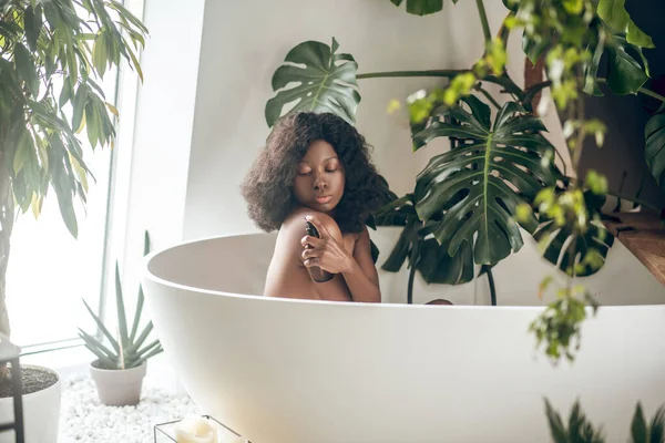 Mulher de pele escura relaxando em um banho e lavando seu corpo — Fotografia de Stock