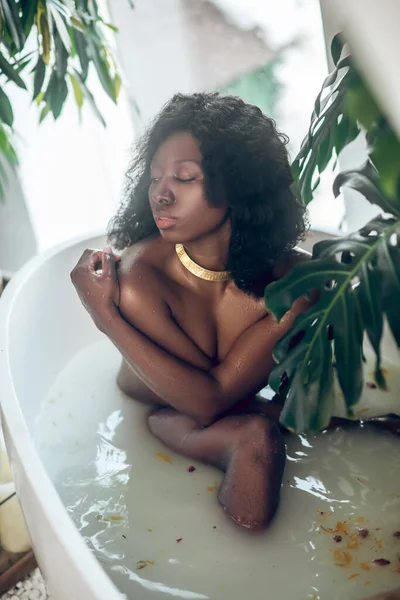 Dark-skinned beautiful naked woman enjoying a bath and looking relaxed — Stock Photo, Image