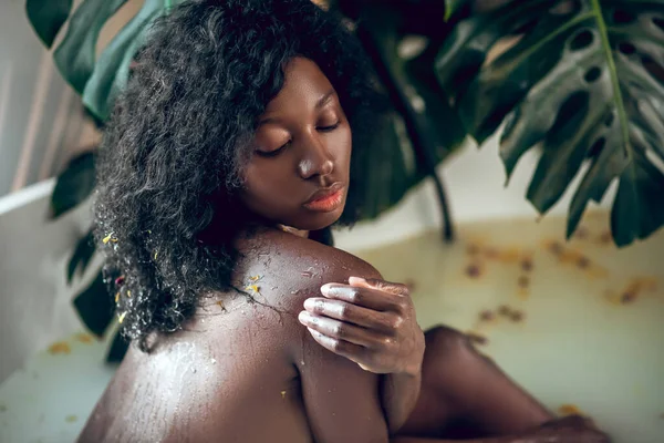 Dark-skinned beautiful naked woman enjoying a bath and looking relaxed — Stock Photo, Image