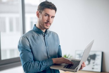 Ofiste çalışan genç bir adam ve meşgul görünüyor.