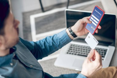 Akıllı telefon tutan ve başvuru yoluyla online ödeme yapan bir adam