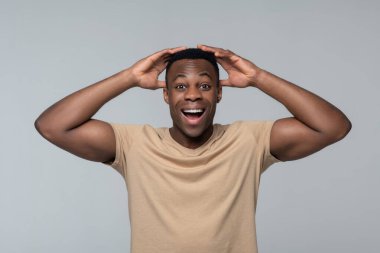 Neşeli, şaşkın adam ellerini başının üstüne kaldırıyor.