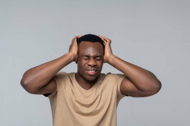 Gözleri kapalı bir adam ellerinin başına dokunuyor.