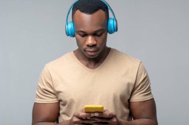 Kulaklıklı, elinde akıllı telefon olan bir adam.