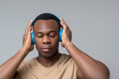 Kulaklıklı, gözleri kapalı konsantre bir adam.