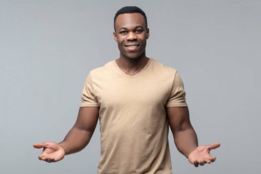 Dost canlısı koyu tenli adam avuçlarını gösteriyor.