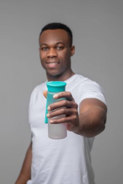 Dost canlısı adam elinde bir şişe su tutuyor.