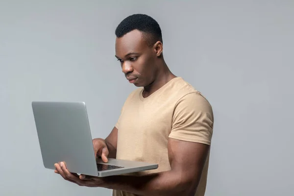 Homem sério olhando para laptop segurando nas mãos — Fotografia de Stock