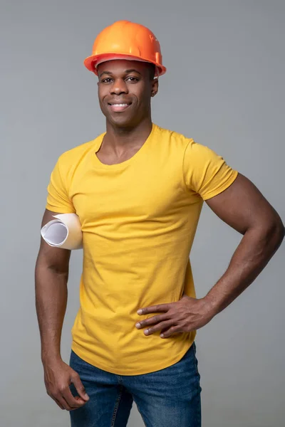 Smiling man in yellow tshirt and protective helmet — Stock Photo, Image