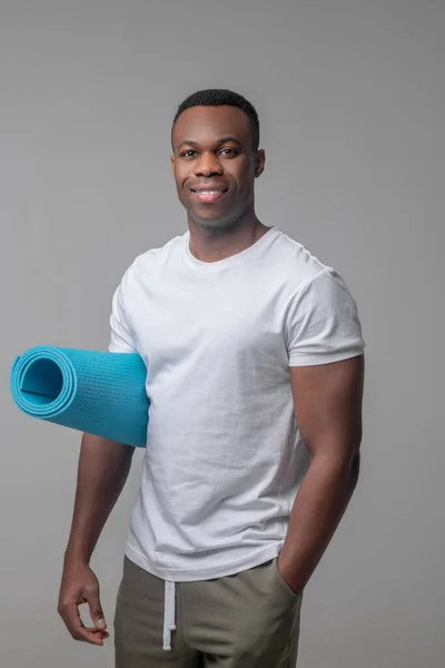 Hombre sonriente de piel oscura con tapete deportivo — Foto de Stock