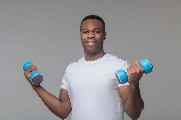 Sonriendo afroamericano de pie con mancuernas en las manos — Foto de Stock