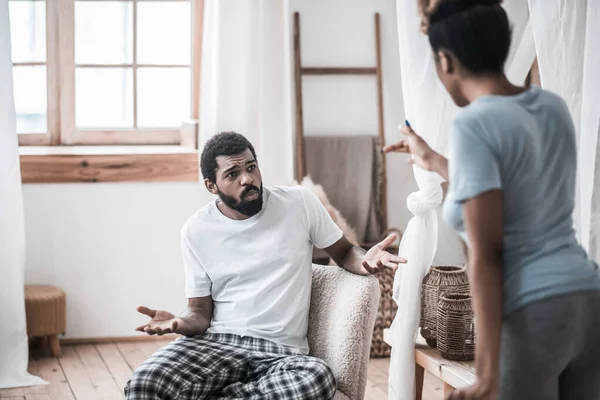 Indignante hombre sentado y esposa de pie con su espalda — Foto de Stock