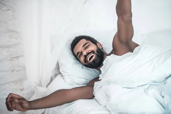 Alegre hombre despierto estirándose en la cama — Foto de Stock