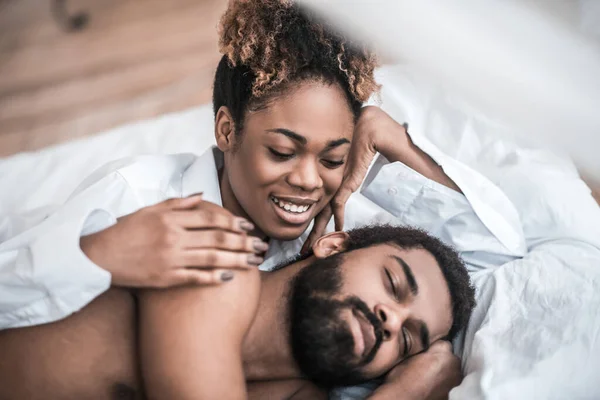 Mulher feliz tocando homem dormindo na cama — Fotografia de Stock