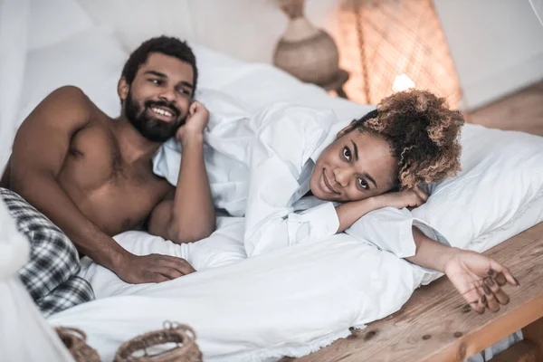 Sötét bőrű nő és férfi otthoni ruhában az ágyban — Stock Fotó