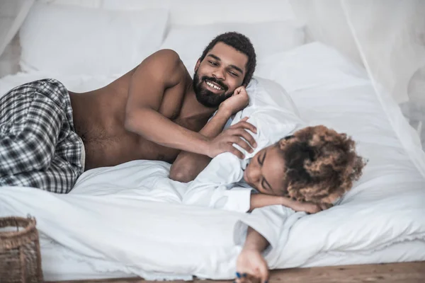 Mosolygó afro-amerikai és mélyen alvó feleség az ágyban — Stock Fotó