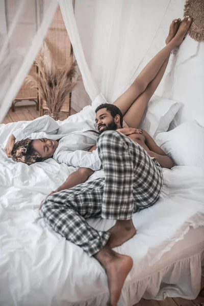 Счастливые мужчина и женщина в домашней одежде на кровати — стоковое фото