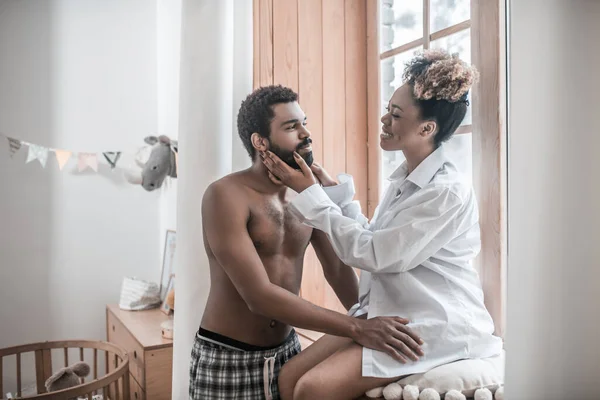 Jolie femme assise sur le rebord de la fenêtre et debout mari — Photo