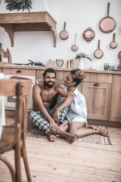 Hombre y mujer sentados en el suelo en la cocina —  Fotos de Stock