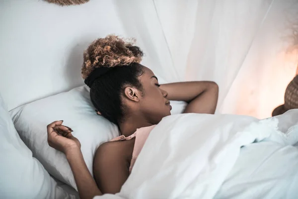 Mujer de piel oscura sonido dormido en la cama blanca — Foto de Stock