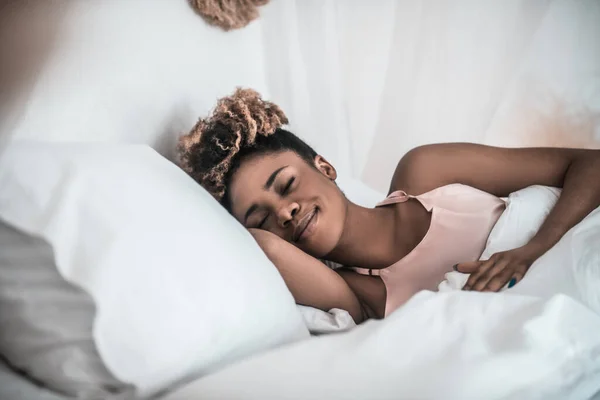 Wanita berkulit gelap tersenyum sambil tidur di tempat tidur — Stok Foto