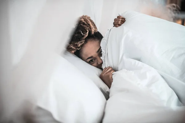 Mujer somnolienta asomándose desde debajo de la manta — Foto de Stock