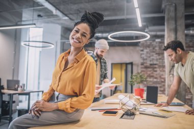 Siyah saçlı, güzel gülümseyen ve mutlu görünen bir kız.