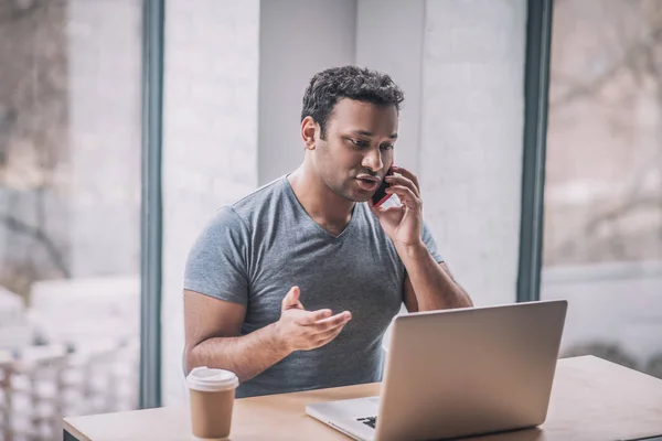 Jonge zakenman werkt aan een laptop en kijkt betrokken — Stockfoto