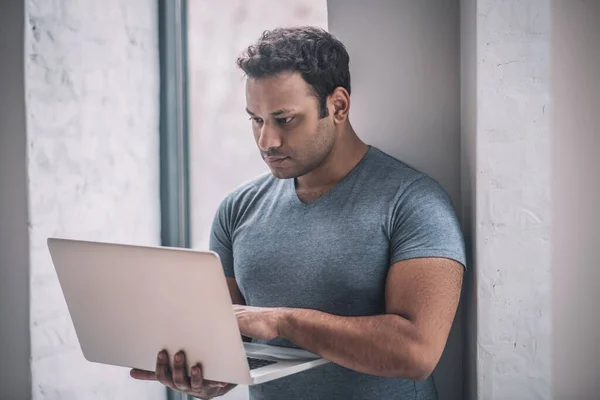 Jonge zakenman werkt aan een laptop en kijkt betrokken — Stockfoto