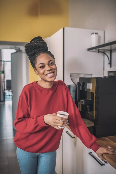 Mulher jovem de pele escura em pé perto da máquina de café — Fotografia de Stock