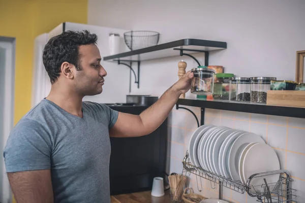 Joven con una camiseta gris haciéndose café — Foto de Stock