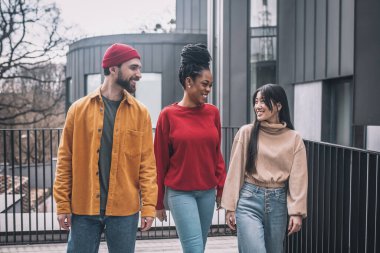 Üç arkadaş sokakta yürüyor ve mutlu görünüyorlar.