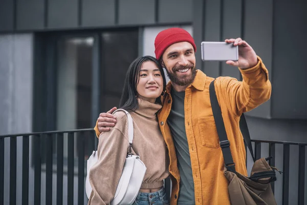 Pareja joven sonriendo y haciendo selfie afuera —  Fotos de Stock