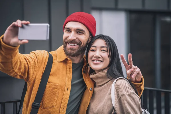 Pareja joven sonriendo y haciendo selfie afuera —  Fotos de Stock