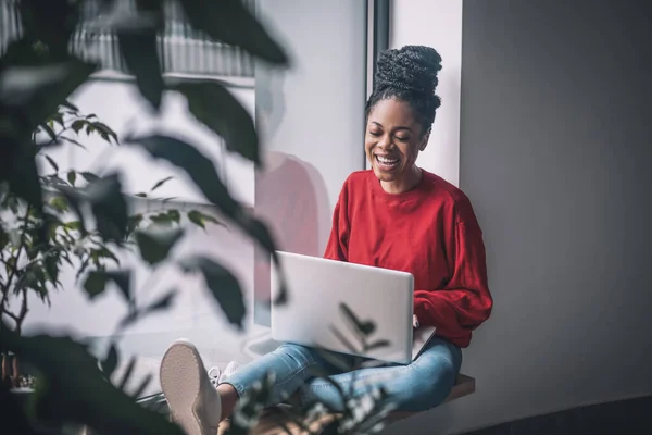 Zwarte vrouw in rood shirt met een laptop — Stockfoto