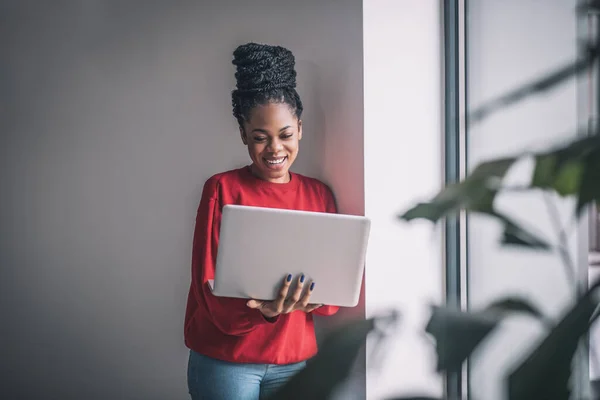 Zwarte vrouw in rood shirt met een laptop die op afstand werkt — Stockfoto