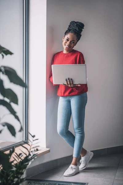 Femme noire en chemise rouge avec un ordinateur portable travaillant à distance — Photo