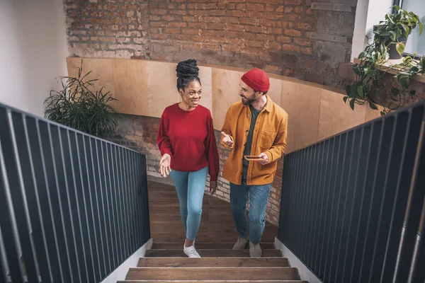 A man in a red hat and a black woman going upstairs