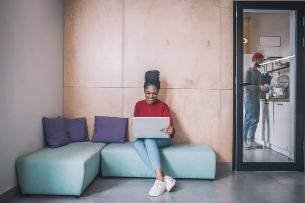 Jeune femme noire assise et travaillant sur un ordinateur portable — Photo