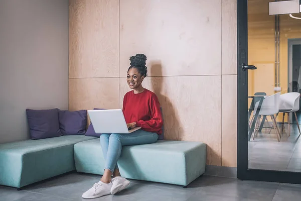 Joven mujer negra sentada y trabajando en un portátil — Foto de Stock